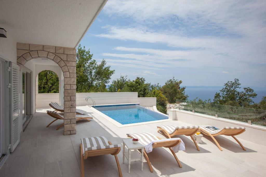 un patio con piscina, sillas y mesa en Villa Retro fusion a luxury villa in Tucepi en Tučepi
