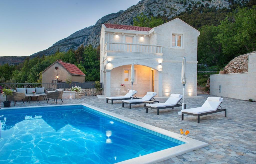 a villa with a swimming pool in front of a house at Luxury villa Atrium in Tučepi, heated pool in Tučepi