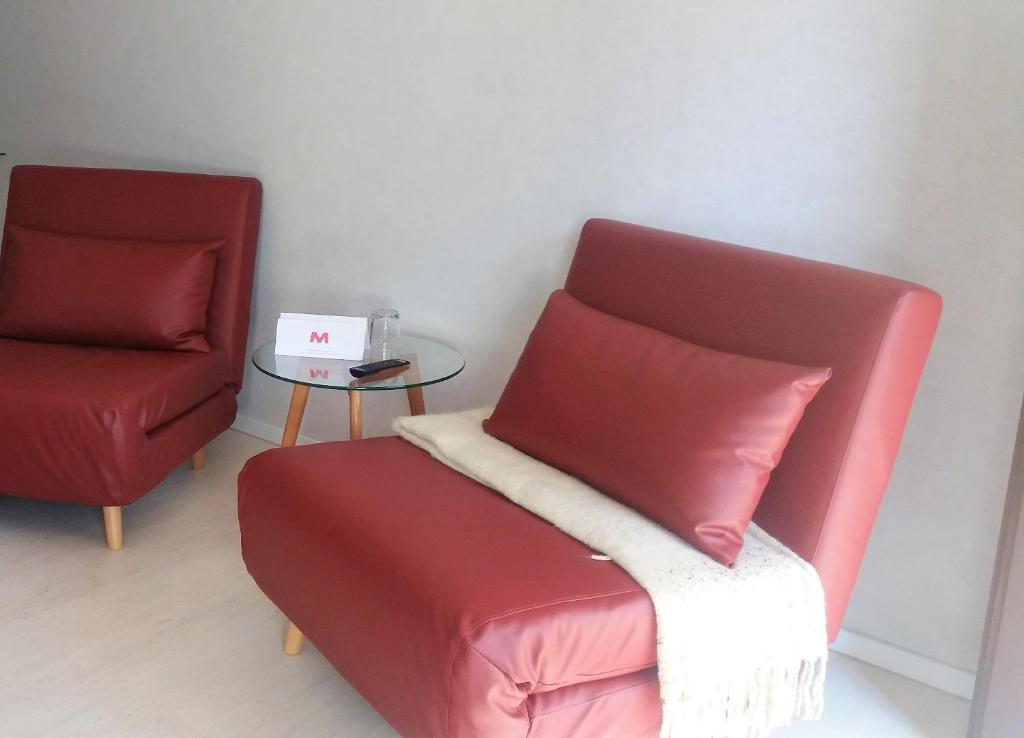ein Wohnzimmer mit einem roten Stuhl und einem Tisch in der Unterkunft Motel in Teterow