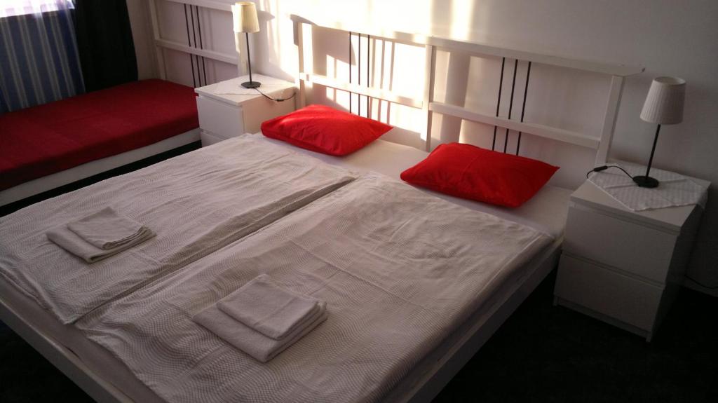 a bedroom with a white bed with red pillows at Apartment Maximilian in Bratislava