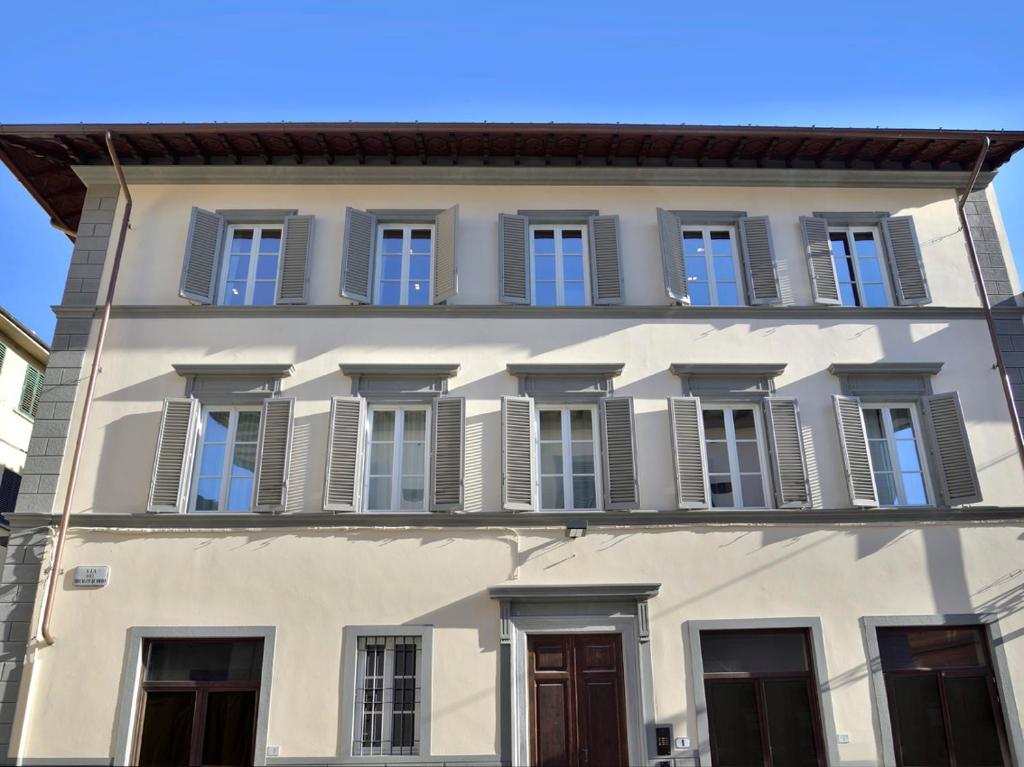 um edifício branco com janelas e persianas azuis em DRAGO d' ORO SUITES em Florença
