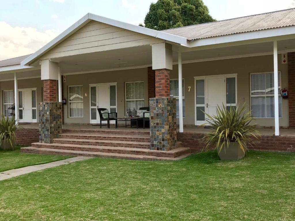 a home with a porch and stairs with grass at Anathi Hotel in Kokstad