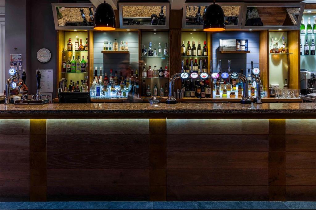 a bar with a lot of bottles of alcohol at The White Lion Hotel in Aldeburgh