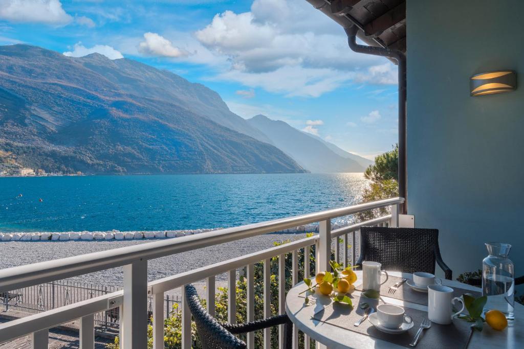a table on a balcony with a view of the water at Casa Toblini al Lago on the beach in Nago-Torbole
