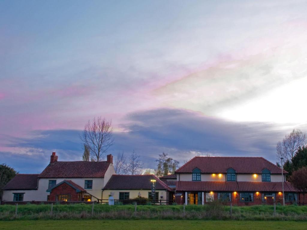 a house with a cloudy sky in the background at Beansheaf Hotel in Pickering