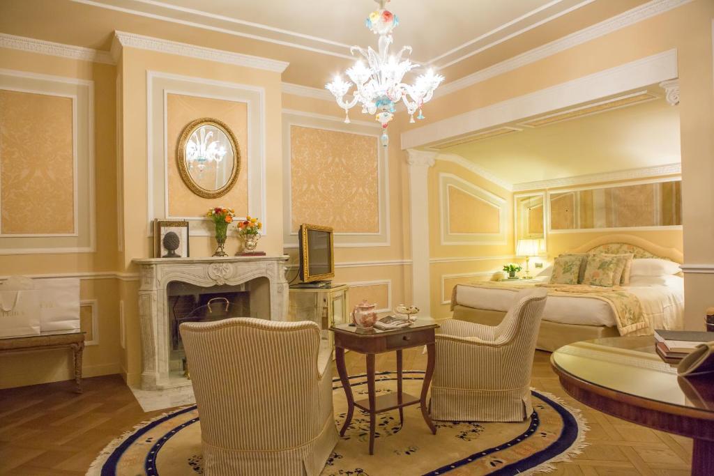 a bedroom with a bed with a fireplace and a chandelier at Grand Hotel Majestic gia' Baglioni in Bologna