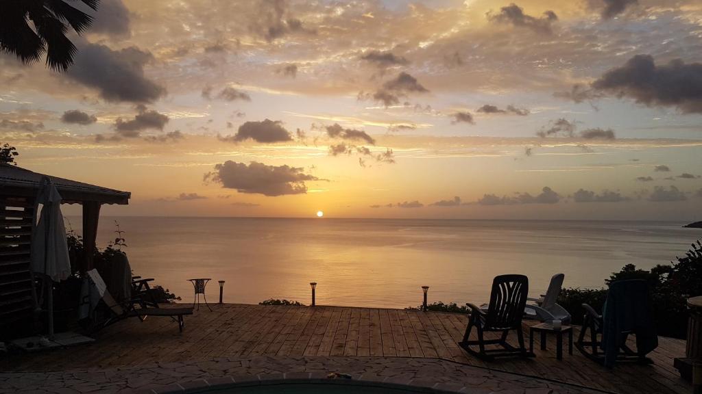 a sunset over the ocean with chairs on a patio at kazAnne in Pointe-Noire