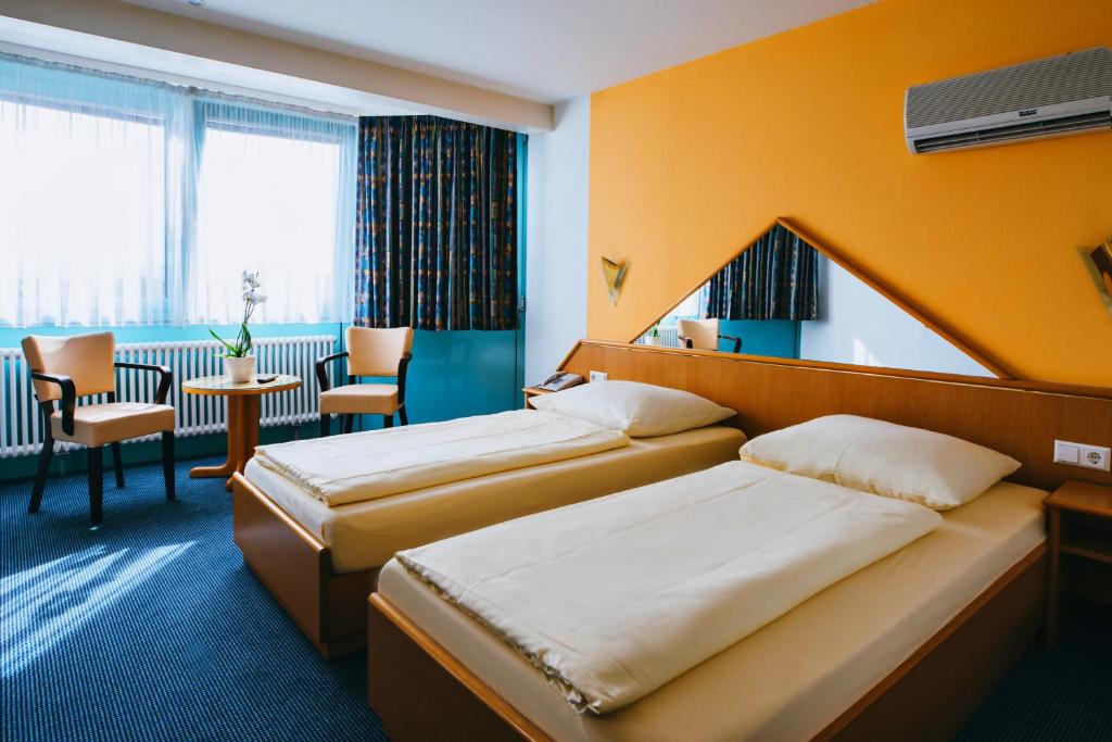 una camera d'albergo con due letti e un tavolo di Hotel Central a Weil am Rhein