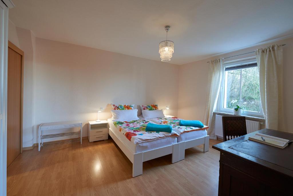 ein weißes Schlafzimmer mit einem Bett und einem Fenster in der Unterkunft Ferienwohnung am Benther Berg in Gehrden