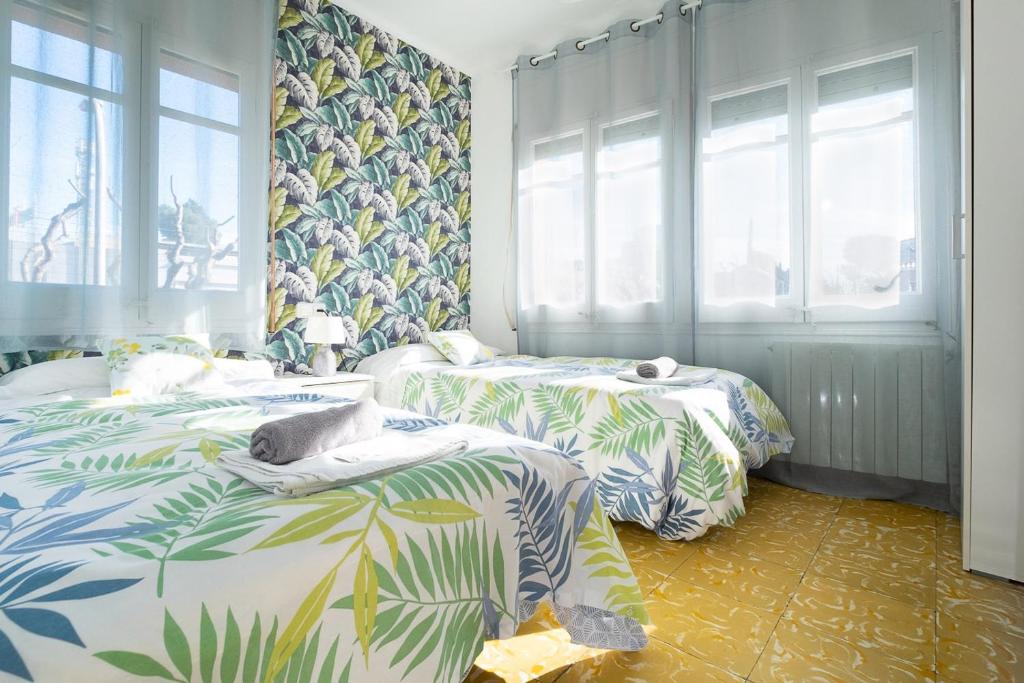 two beds in a room with tropical wallpaper at Fonda Chavarria in Sant Joan Despí