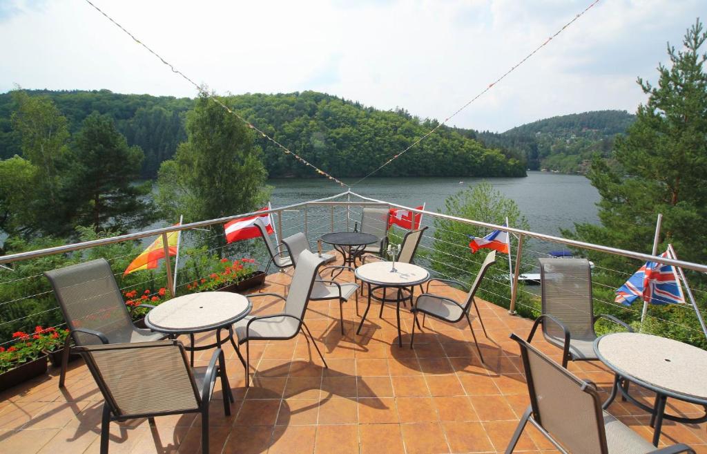 a balcony with tables and chairs with a view of a river at Hotel Laguna Slapy in Netvořice