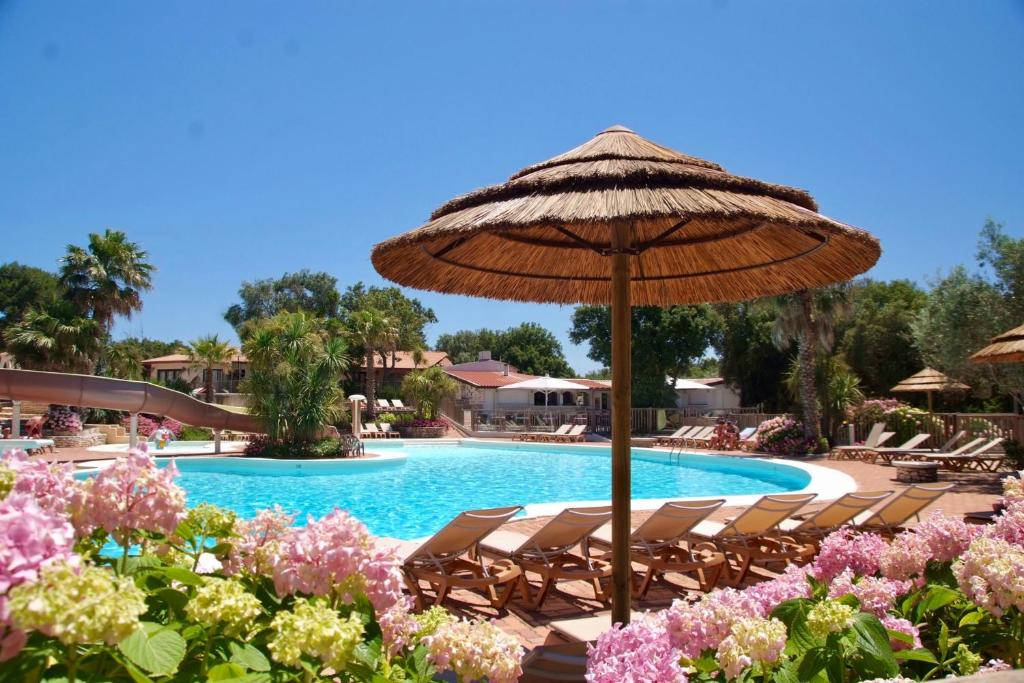 a swimming pool with chairs and an umbrella at Les Suites De Pertamina in Bonifacio