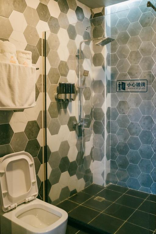 a bathroom with a toilet and a glass shower at Saipan Skyline Designers Hotel in Saipan