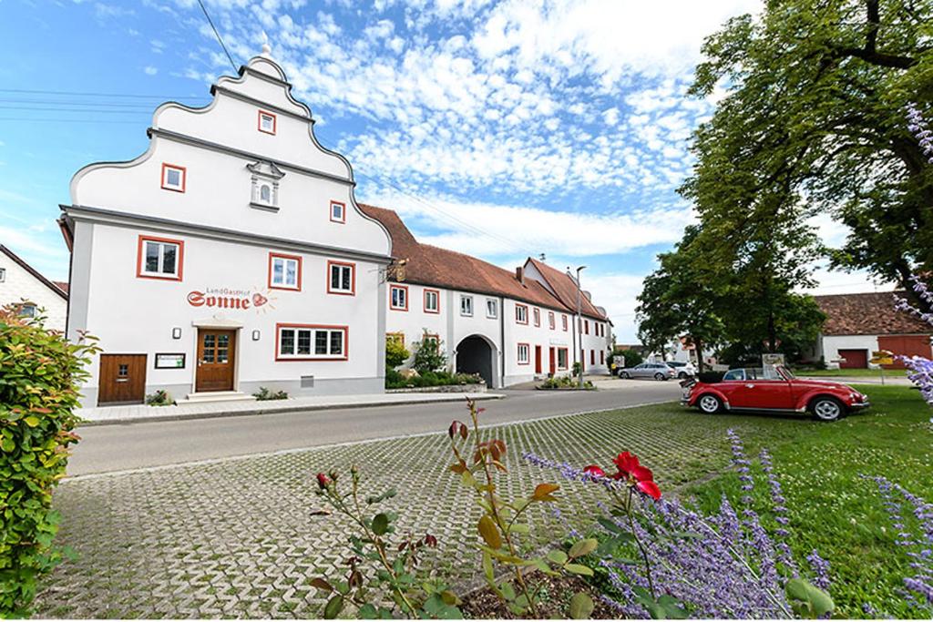 a red car parked in front of a white building at Landgasthof Zur Sonne in Fünfstetten