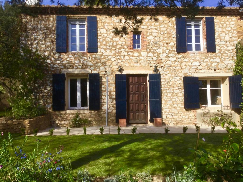 ユゼスにあるXIXe Provencal Stone House with Private Pool near Uzesの青いシャッターと庭のある古い石造りの家