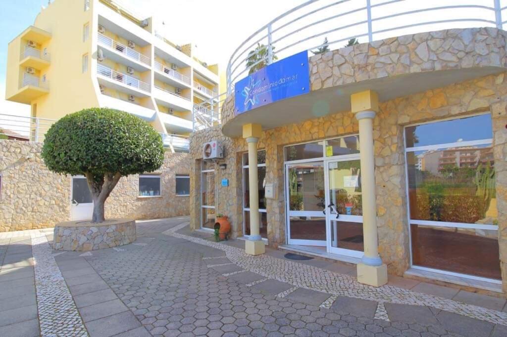 a building with a tree in front of it at Condominio do Mar in Lagos