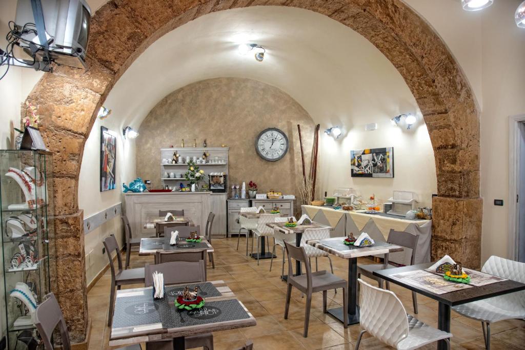 un restaurant avec des tables, des chaises et une horloge dans l'établissement Bed & Breakfasts Conte Perollo, à Sciacca