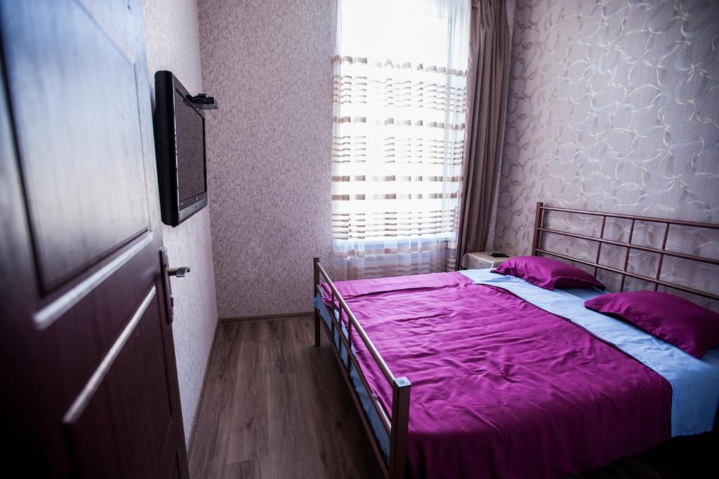 um quarto com uma cama com lençóis roxos e uma janela em Guest House Didis em Tbilisi