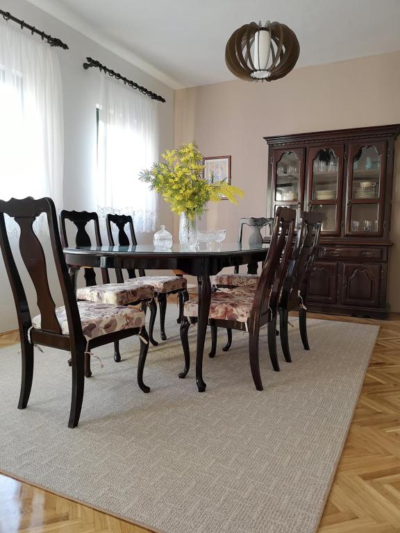 a dining room with a table with chairs and a vase of flowers at Apartments Ivona in Trogir