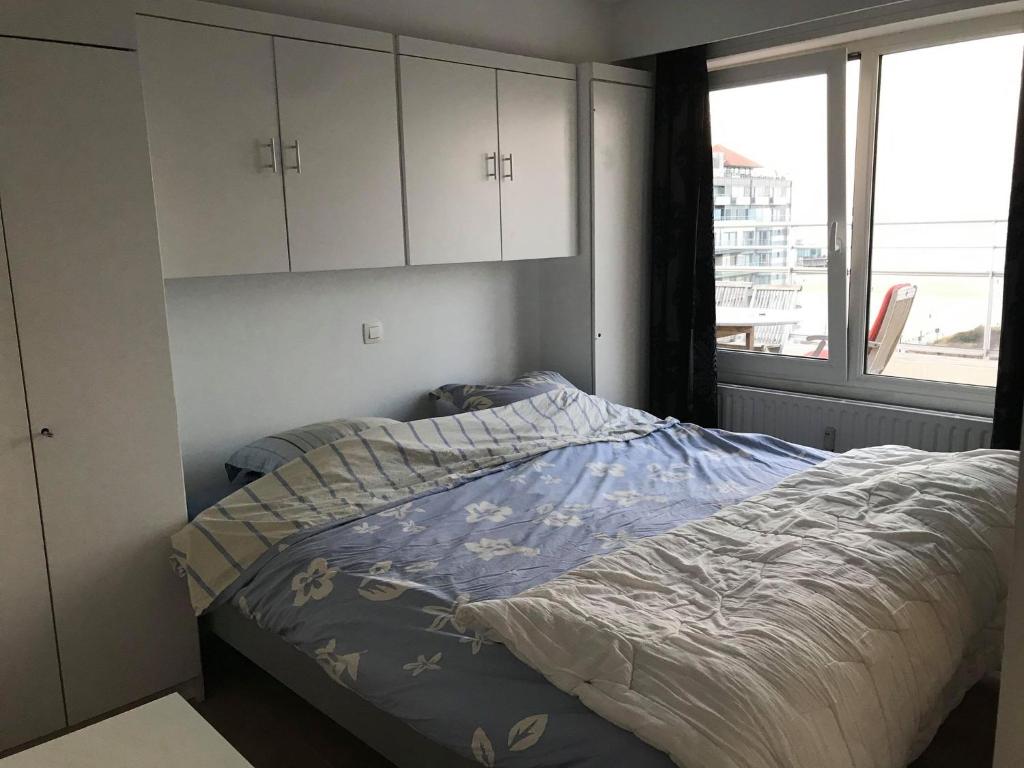 a bedroom with a bed and cabinets and a window at Penthouse Poseidon in Blankenberge