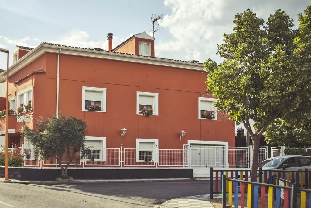 un edificio rojo con ventanas blancas en una calle en CASA RURAL EL SAUCE. A 2,5 KM DE CUENCA CAPITAL en Nohales