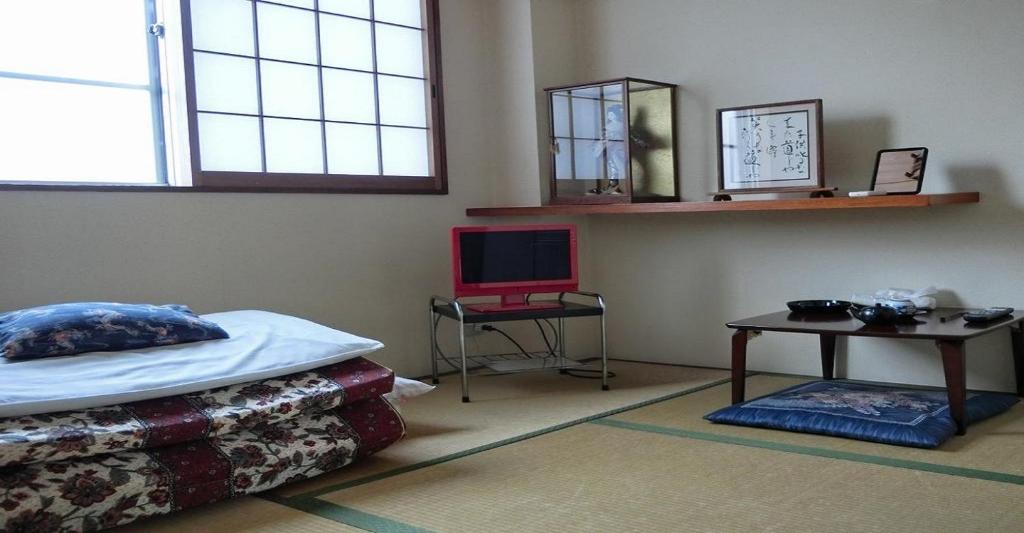 a bedroom with a bed and a table with a laptop at Ryokan Suzukisou-tatami room No bath and toilet- Vacation STAY 17862 in Kyoto