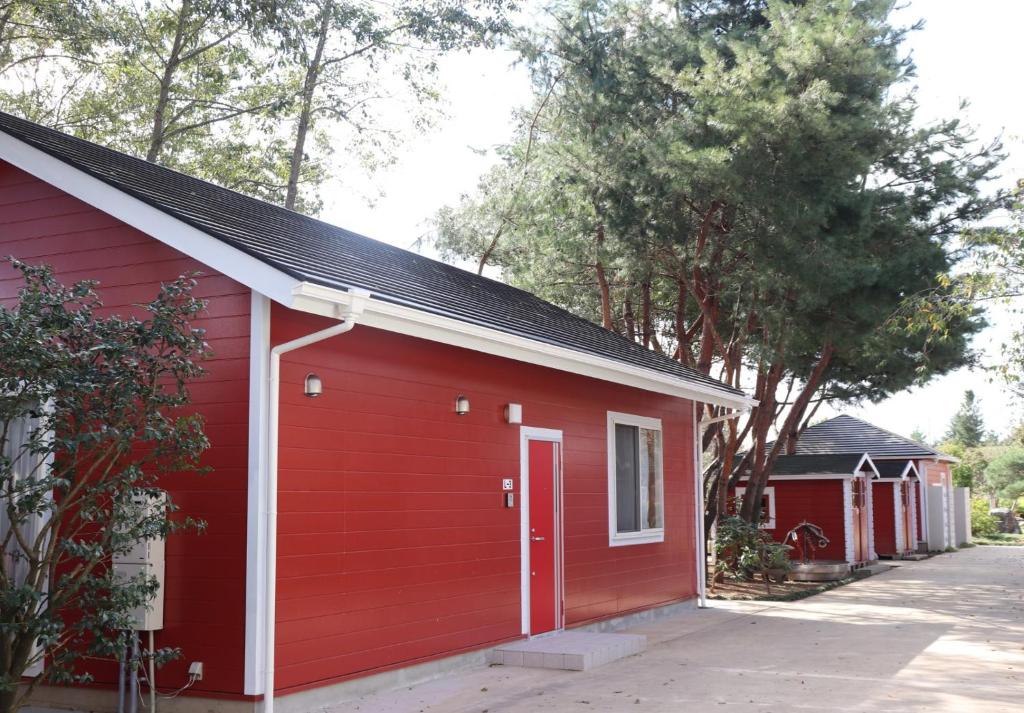 un garage rosso con una porta rossa e alberi di The Hirosawa City Dome House West Building / Vacation STAY 18763 a Chikusei