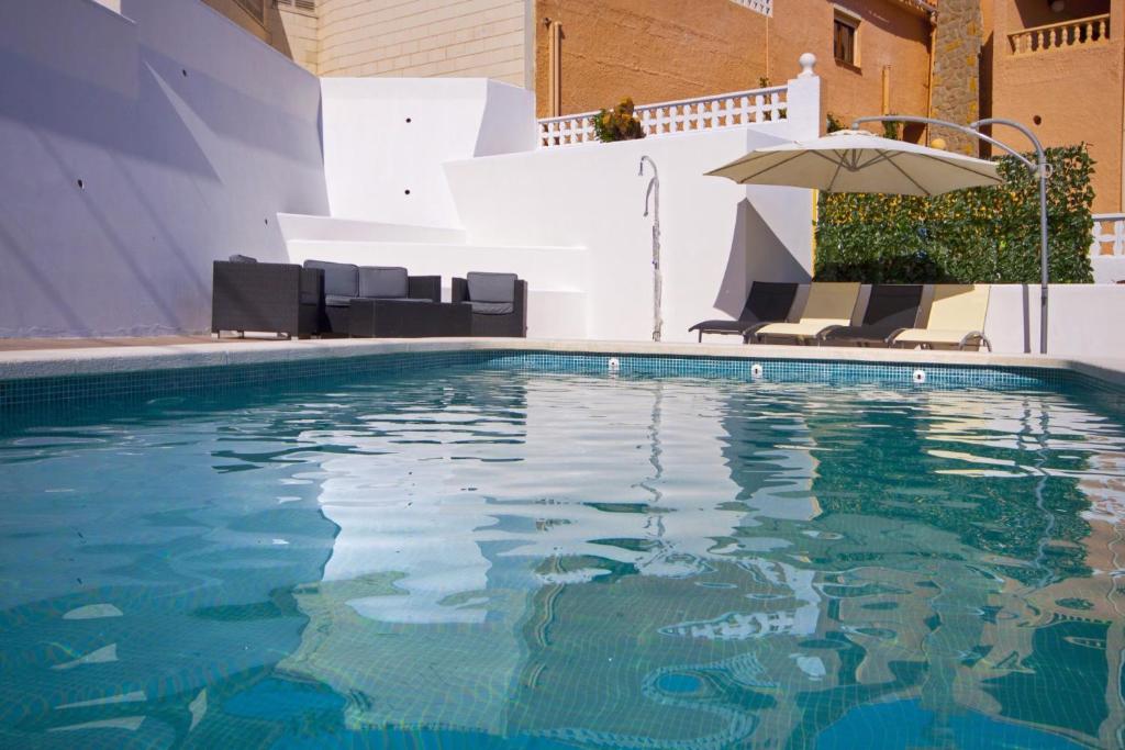 a swimming pool with chairs and an umbrella at Villa Jazmin in Calpe