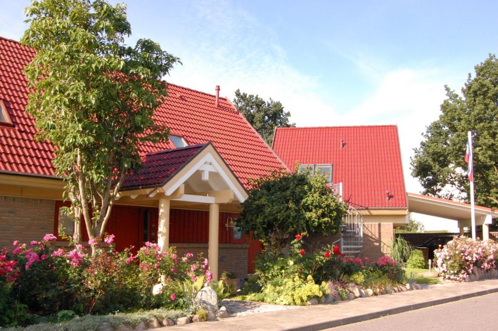 a house with a red roof and some flowers at Landhaus Tönning in Damp