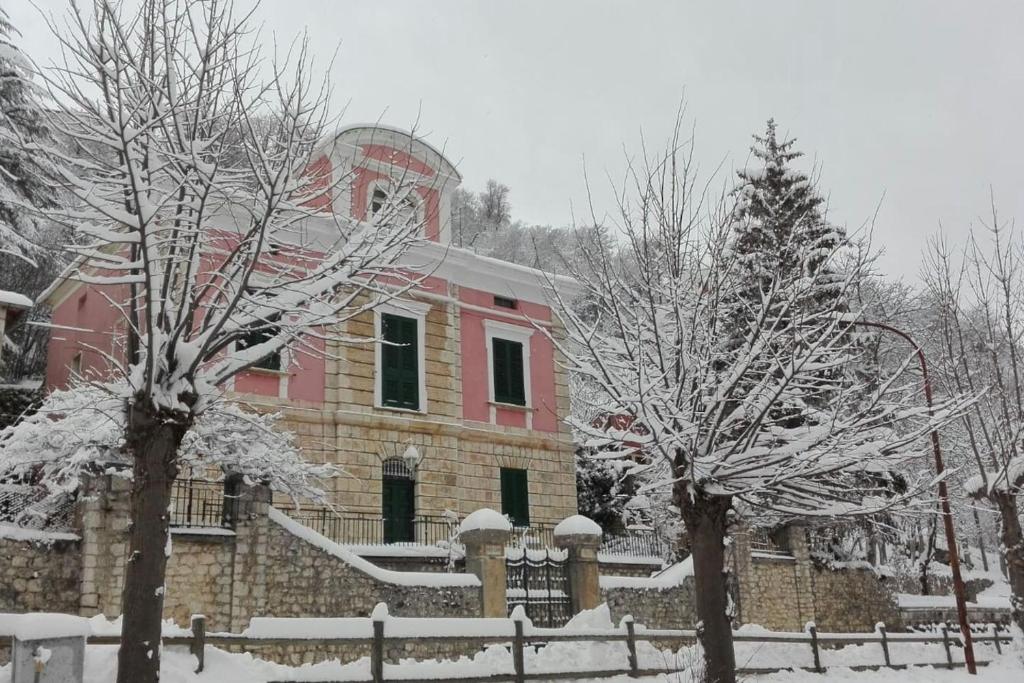 RoccamandolfiにあるLa Dimora del tempo ritrovatoの雪の中に時計塔のある赤い建物