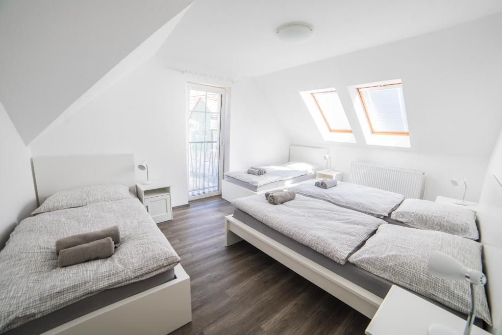 two beds in a bedroom with white walls and wooden floors at Apartmány U parku Třeboň in Třeboň