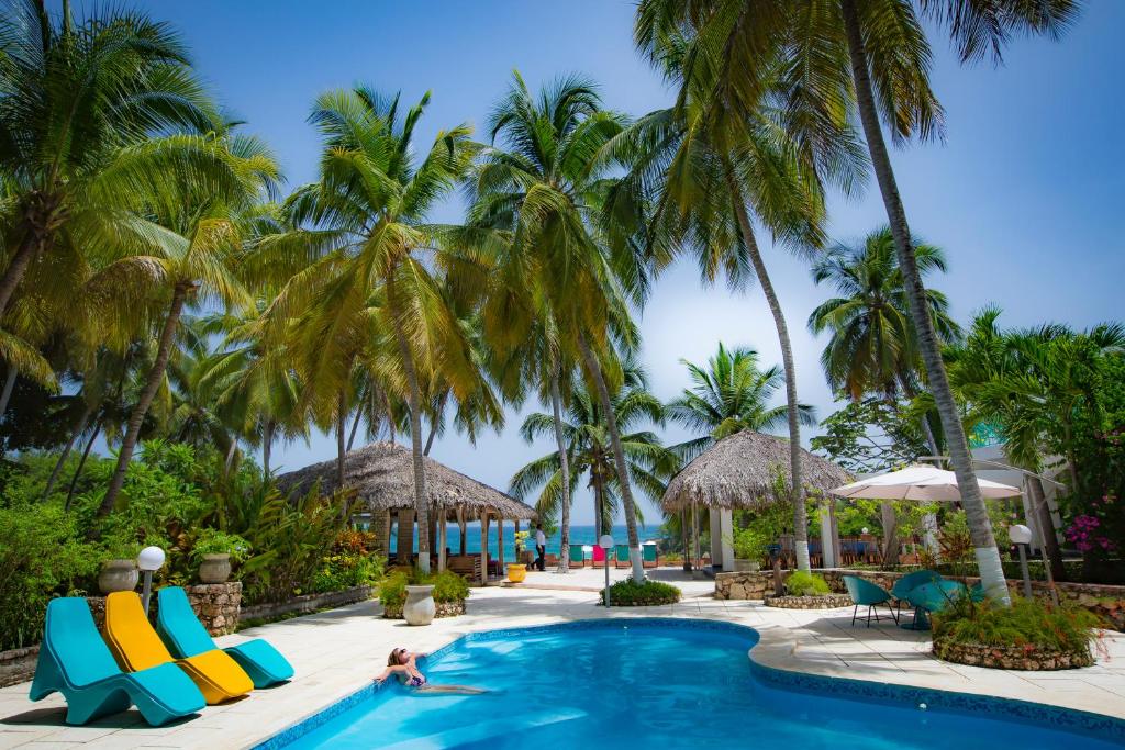 una mujer nadando en una piscina en un complejo con palmeras en Hotel Restaurant Cyvadier Plage en Jacmel