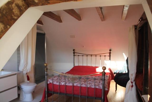 sypialnia z czerwonym łóżkiem na poddaszu w obiekcie Le Moulin de Benechou w mieście Olemps