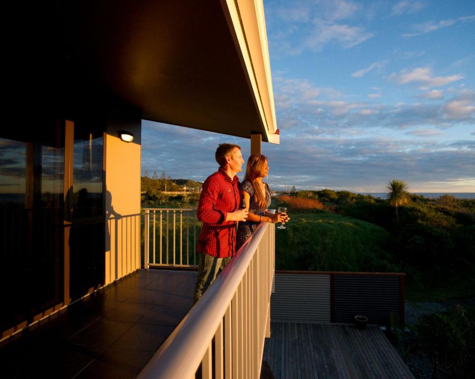 a man and woman standing on the balcony of a house at Luxury Seaview Apartments in Greymouth