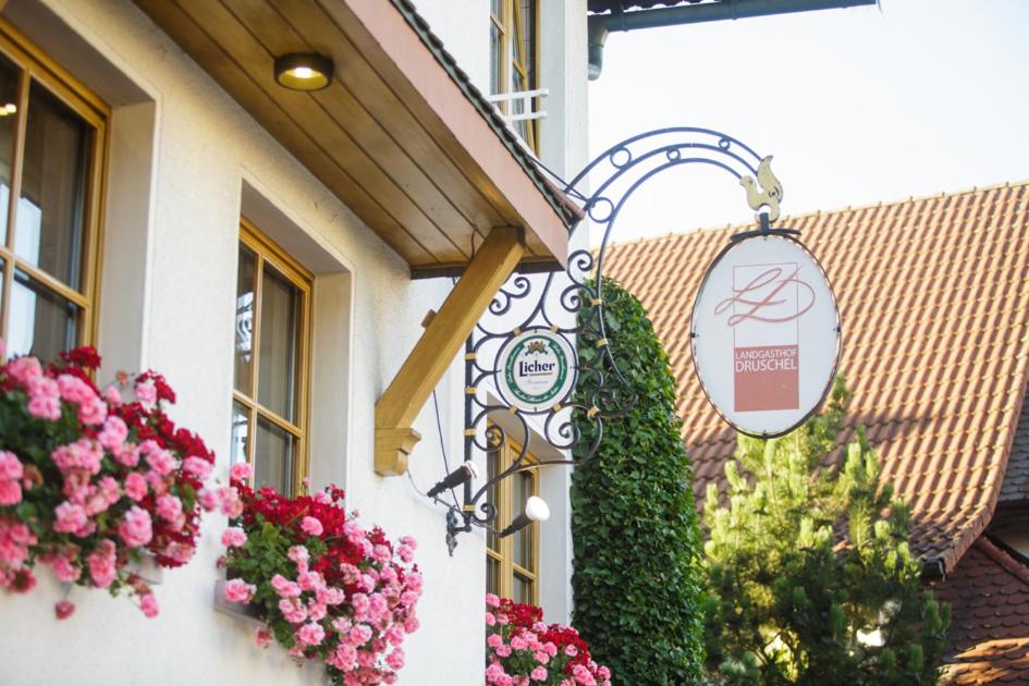 a sign on the side of a building with flowers at Landgasthof Druschel in Schlüchtern