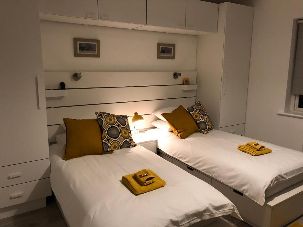 Duas camas num pequeno quarto com almofadas amarelas em Elm Grove em Schull