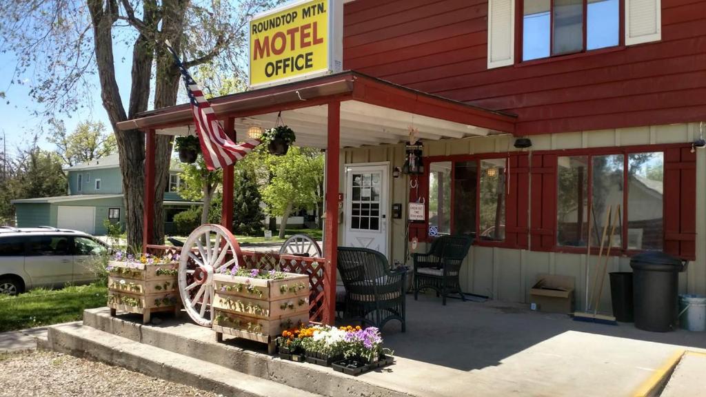 a motel office with a sign and flowers in front of it at Roundtop Mountain Vista - Cabins and Motel in Thermopolis