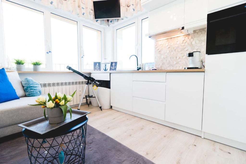a kitchen with white cabinets and a table with flowers on it at Warszawska 15 Apartament in Gdynia