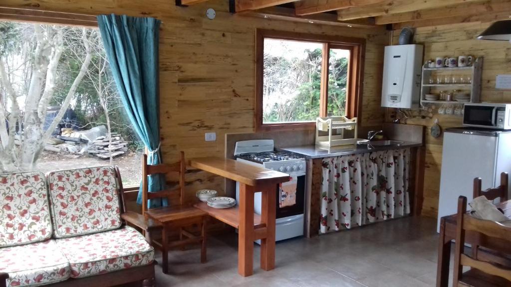 a kitchen with a stove and a table and a couch at Cabañas Villa Centauro in San Carlos de Bariloche