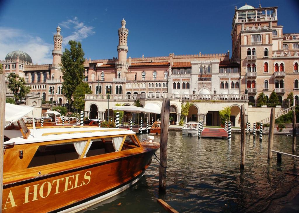 a boat in the water in front of a building at Hotel Excelsior Venice in Venice-Lido