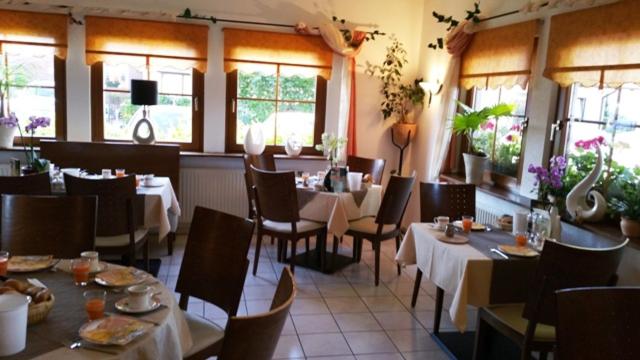 un comedor con mesas, sillas y ventanas en Hotel Birkenhof Garni, en Baabe