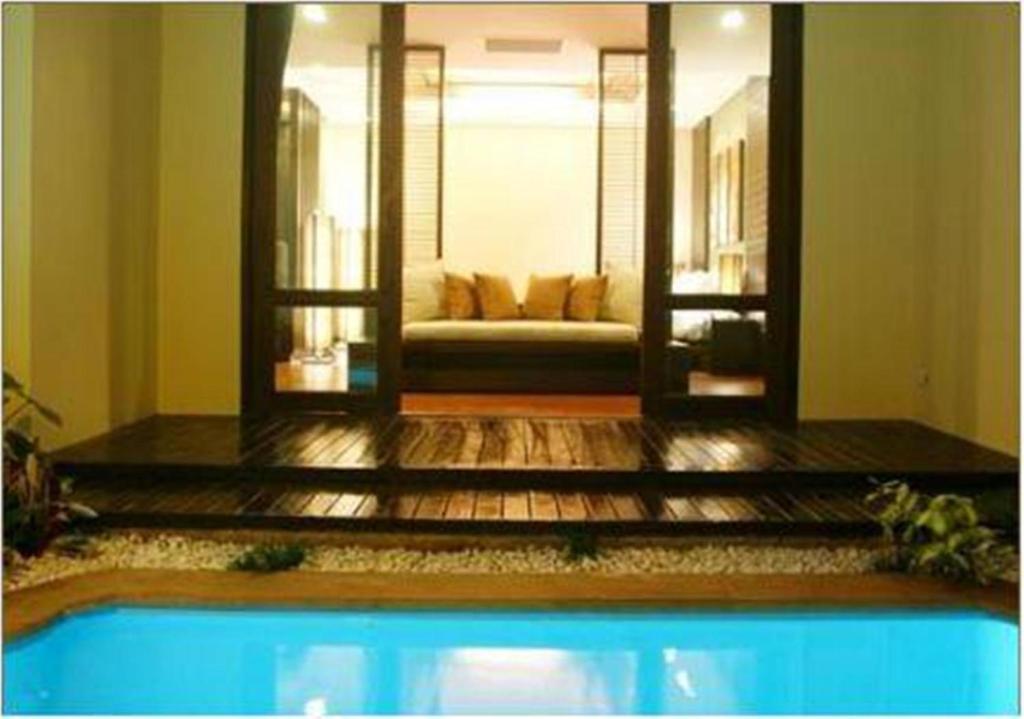 a swimming pool in a living room with a couch at Yodia Heritage Hotel in Phitsanulok