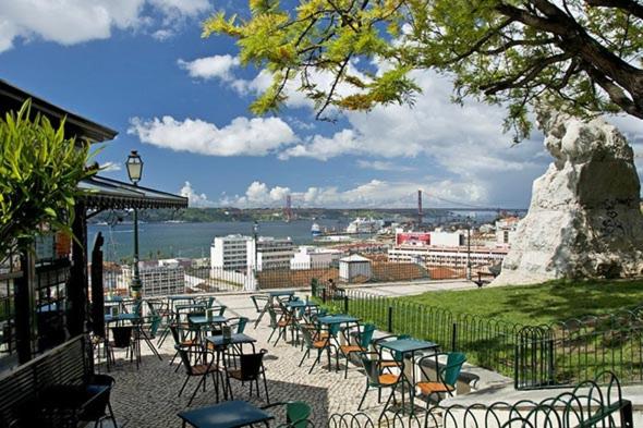 d'une terrasse avec des chaises, des tables et une masse d'eau. dans l'établissement Auristelas Hostel, à Lisbonne