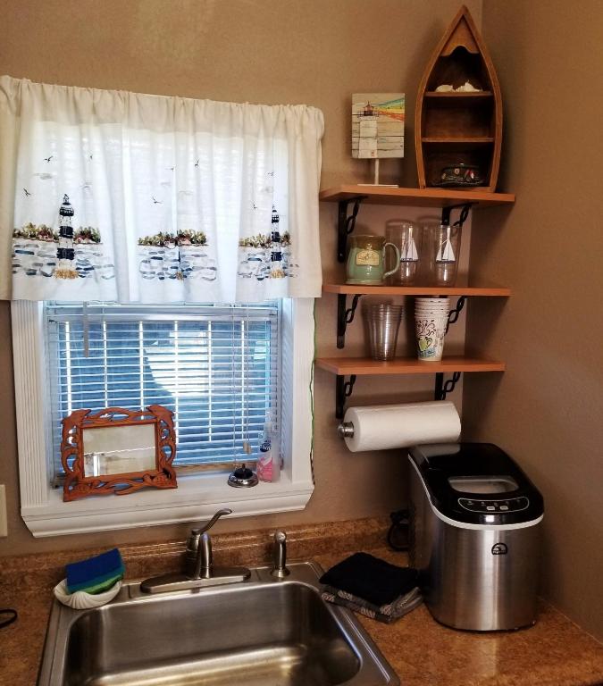 um balcão de cozinha com um lavatório e uma janela em Come Friday Cottages em Bacliff