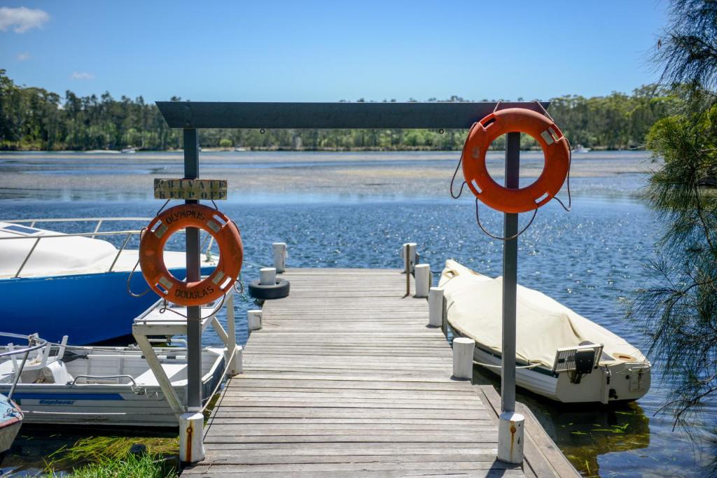 a dock with two boats on the water at Calm Waters Waterfront Cottages in Sussex Inlet