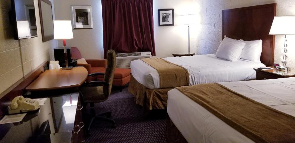 a hotel room with two beds and a desk at Cedar Inn Motel in Cavalier