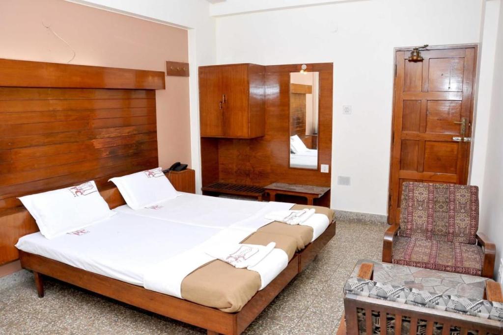 a bedroom with a large bed and a chair at PRANAM COMFORTS LODGE in Bangalore