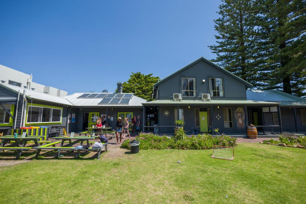 a house with a yard with picnic tables in front of it at Dunsborough Beachouse YHA in Dunsborough