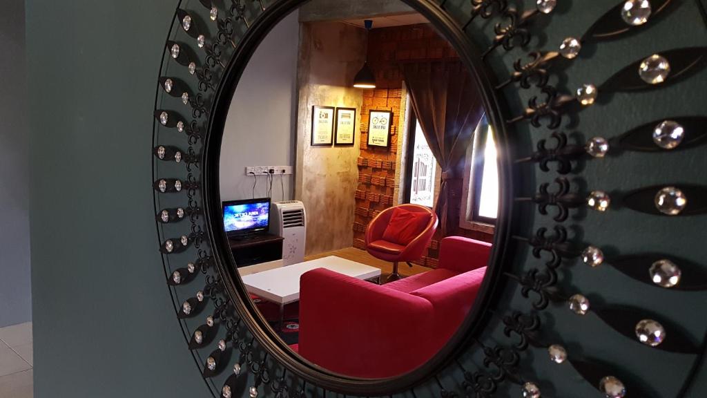 um reflexo de espelho de uma sala de estar com uma cadeira vermelha em Andak Home2stay em Ipoh