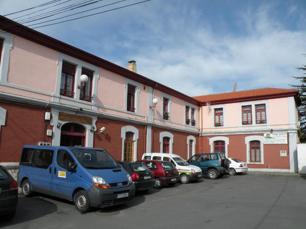 eine Reihe von Autos, die vor einem Gebäude geparkt sind in der Unterkunft Albergue La Estación in Llanes